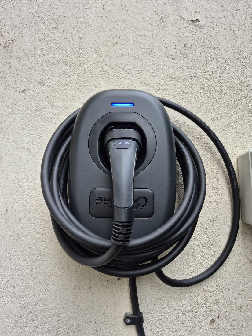 Home EV charger mounted on an exterior wall with the cable coiled and stowed